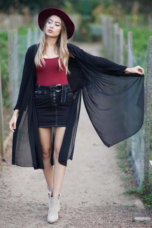 A woman wears ankle cowboy boots with a short skirt, red toe and light coat
