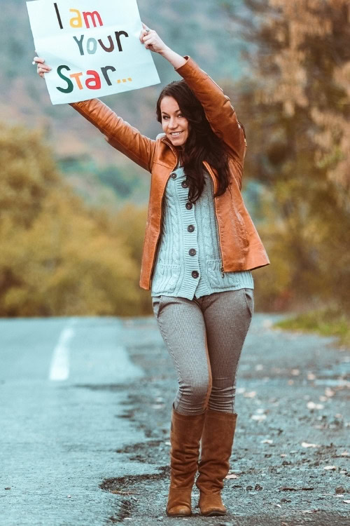 a woman wears brown cowboy boots with jeans and brown leather jacket