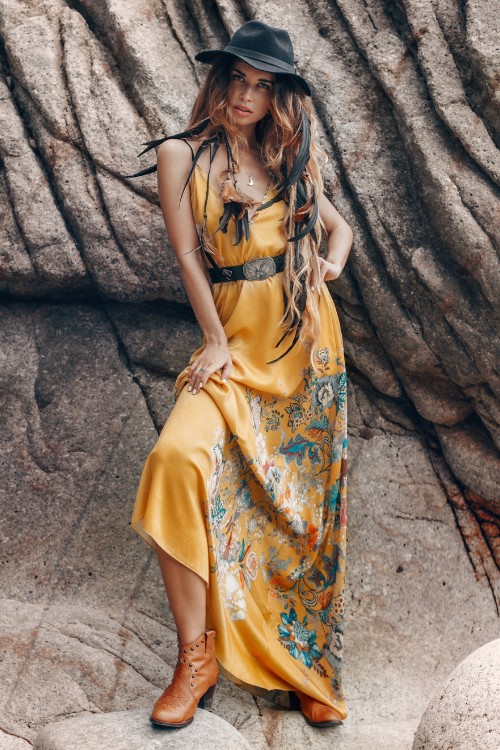 A woman wears flowy long dress with brown cowboy boots