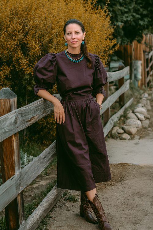 A woman over 30 in a full-body dark plum midi dress with a tonal western yoke seam and puffed sleeves