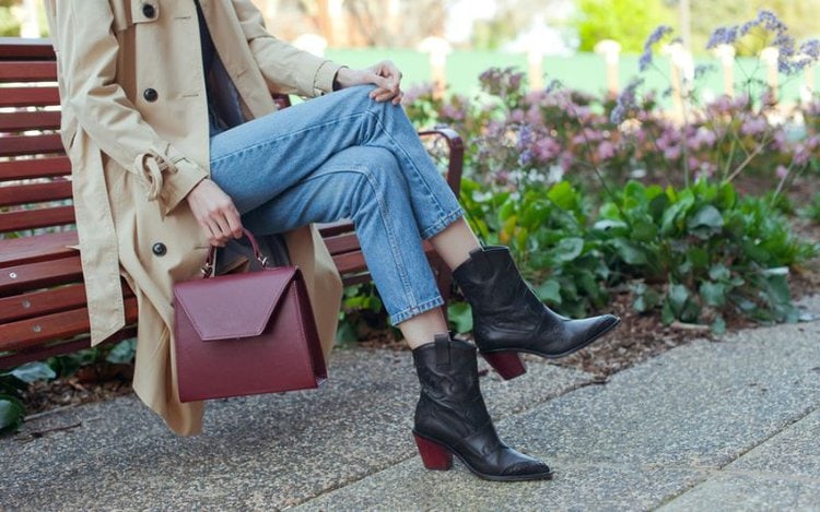 A woman wear jeans with black cowboy boots and a blazer