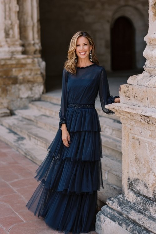a woman over 50 in a navy chiffon gown with a layered tiered skirt, beaded cuffs, and illusion bateau neckline
