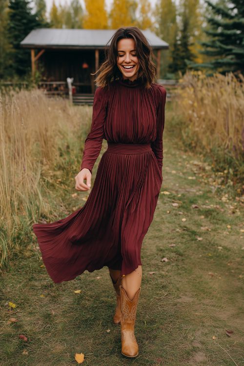 A woman wears a burgundy high-neck pleated dress with tan western boots