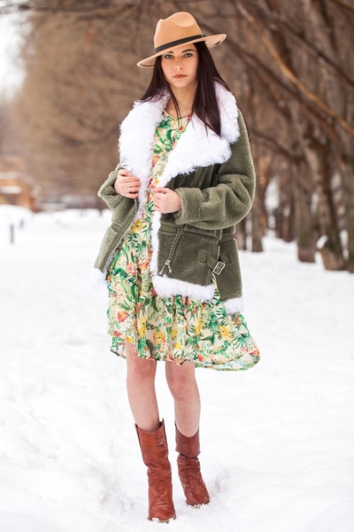 a woman wears cowboy boots with a pattern dress and warm coat for winter