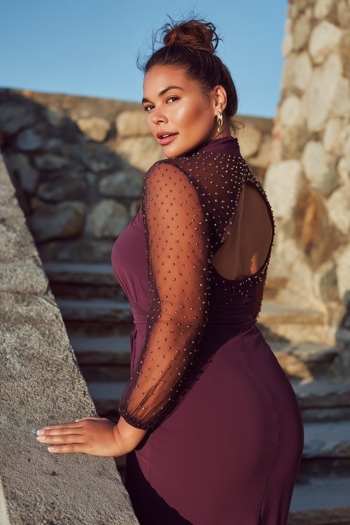 A plus-size woman wears a plum high-neck midi dress with a cut-out back and sheer sleeves embroidered with scattered gold dots