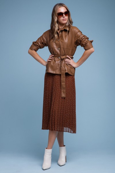 A woman wears white ankle cowboy boots with skirt and leather top