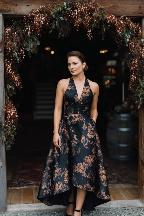 a woman in a black floral jacquard cocktail dress with structured bodice and flared skirt
